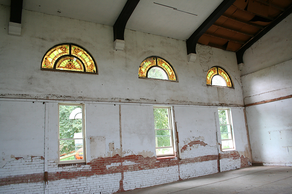 Exposed weathered bricks and broken stained glass can be seen.