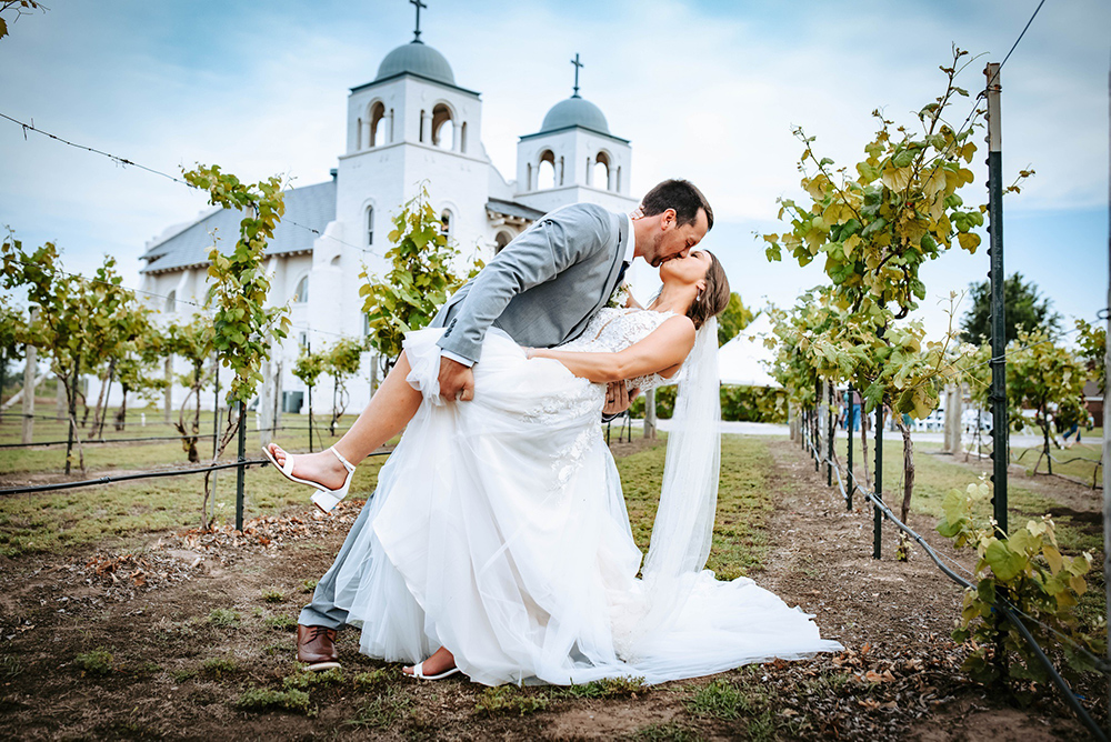 A bride and groom kiss in the vineyard