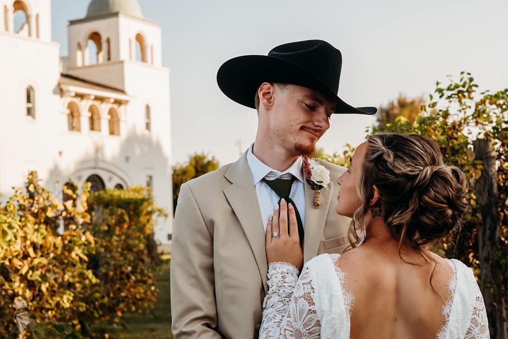 A bride looks up at her groom in his cowboy hat